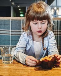 Portrait of girl with muffin on table
