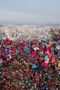 Multi colored padlocks hanging on city against sky