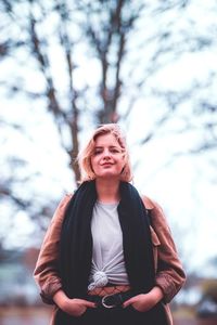 Portrait of teenage girl standing against tree