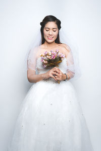 Young woman standing against white wall