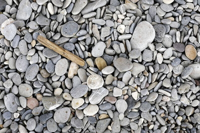 Close up on stones at the beach, from above, flat lay, natural background, pebbles, gray, monochrome 