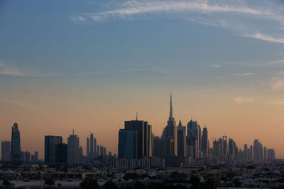 Modern buildings in city against sky during sunset