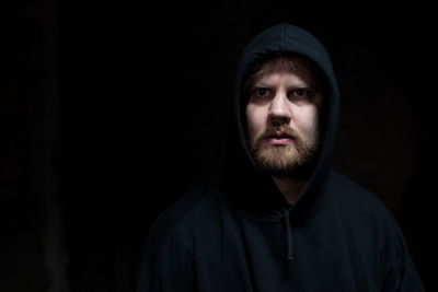 Portrait of young man against black background