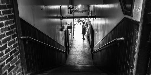 Rear view of man walking on staircase in building