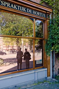 Rear view of two people standing in front of building