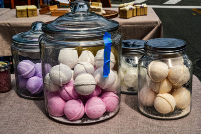 Big jars of artisan made bath bombs in pastel colors on outdoor table at farmer's market