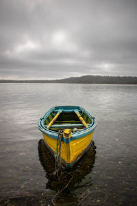 Boat moored in water against sky