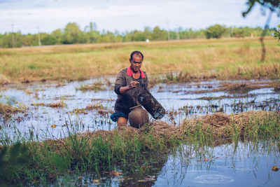 Full length of man sitting on grass by lake