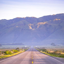 Road leading towards mountains against sky