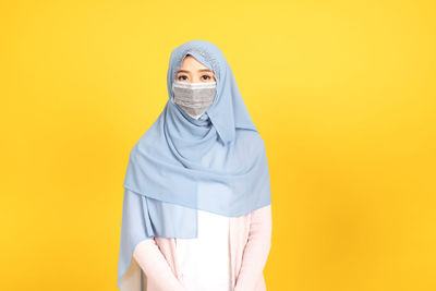 Portrait of mid adult woman against yellow background