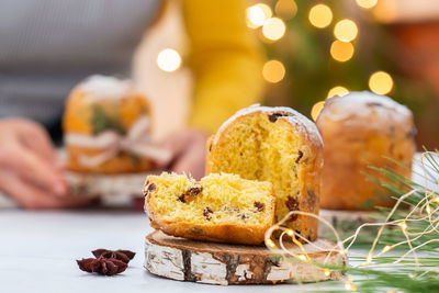 Traditional italian christmas cake panettone on a rustic table. female hands are holding cake