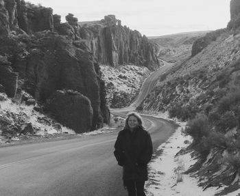 Smiling mid adult woman with hands in pockets walking on road during winter