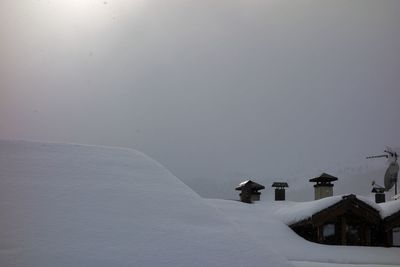 Houses by snow against sky during winter