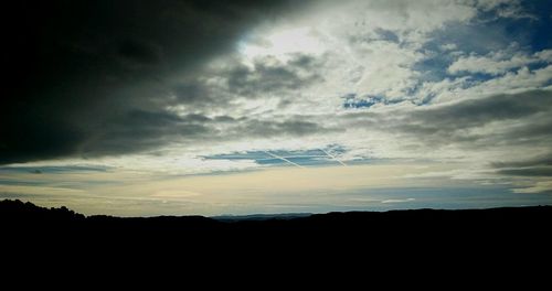 Silhouette of landscape against cloudy sky