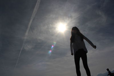 Low angle view of silhouette woman standing against sky