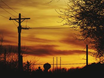 Low angle view of electricity pylon against dramatic sky