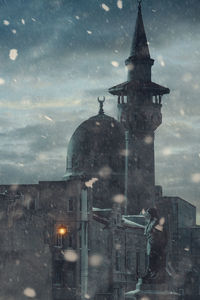 Tower amidst buildings in city during rainy season