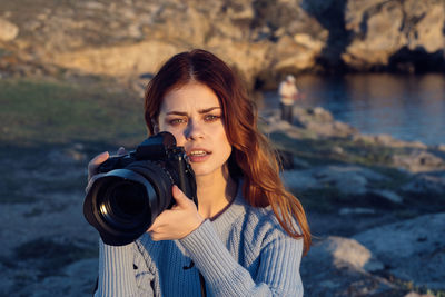 Portrait of young woman photographing camera
