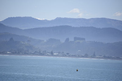 Scenic view of sea by mountains against sky