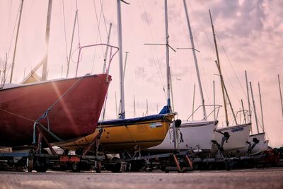 Sailboats moored at harbor against sky during sunset