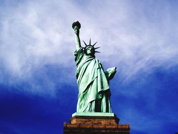 Low angle view of statue of liberty against cloudy sky