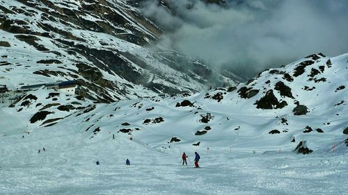 People on snowcapped mountain against sky