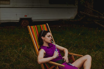 Woman igniting cigarette while sitting on chair