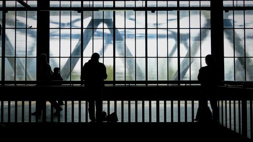 Silhouette people standing by railing