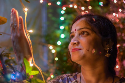 Smiling woman holding string light at night