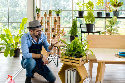 Young man sitting on chair by potted plant