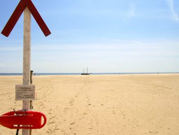 Close-up of road sign on beach against sky