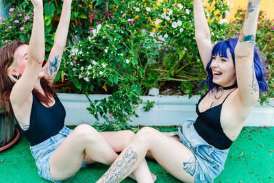 Happy young women playing patty cake in backyard