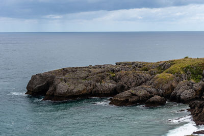 Rock formation in sea against sky