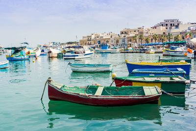 Boats moored at harbor against sky