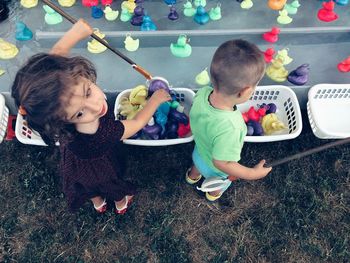 Siblings collecting toys in baskets against pond