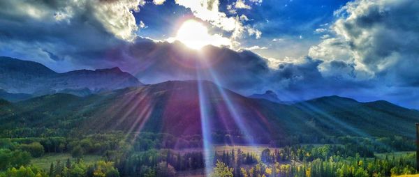 Sun shining through clouds over mountain