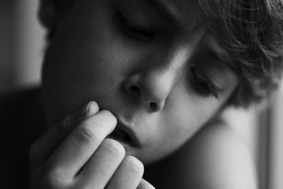 Close-up of boy with finger in mouth thinking