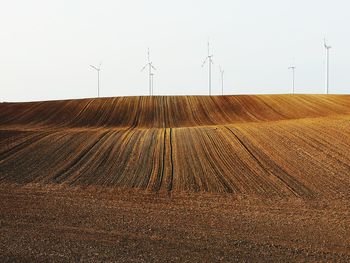 Wind turbines on field against sky