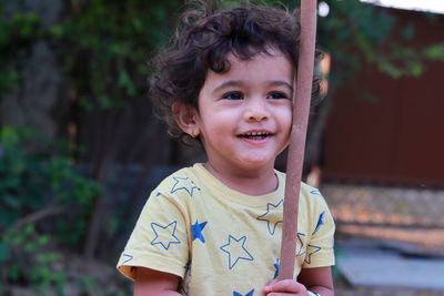 An indian little child is playing with a wooden stick and laughing