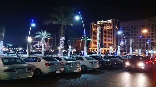 Cars on illuminated city street against sky at night