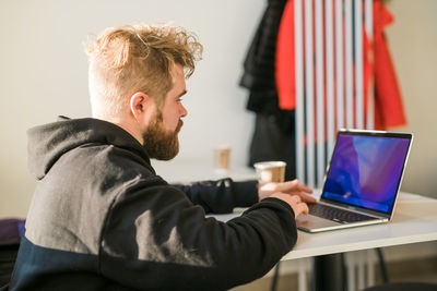 Side view of man using laptop at home