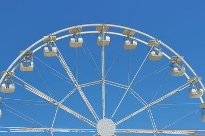 Low angle view of ferris wheel against clear blue sky