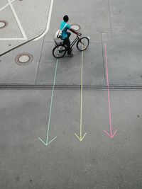 High angle view of man cycling over arrows symbols on street