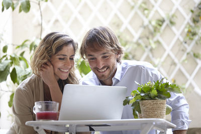 Businessman and woman co-working on laptop outdoors