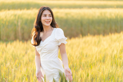 Happy young beautiful asian woman in white dress standing in the barley field, lifestyle concept