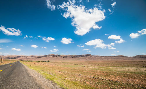 Road amidst field against sky