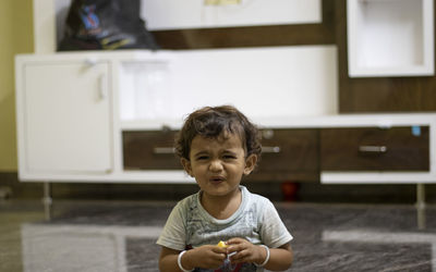 A child eats mangoes, showing it as sour with his mouth