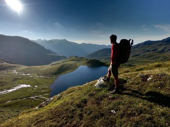 Side view of backpacker standing on mountain against sky