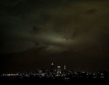 Illuminated cityscape against cloudy sky