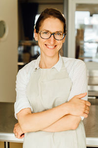 Portrait of female chef in glasses and apron smiling at camera